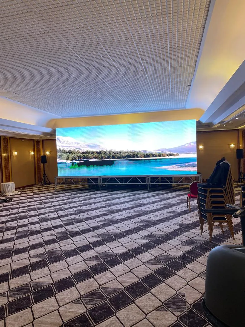 Un mur d'écran LED allumé au fond d'une salle de conférence vide, avant l'arrivée du public